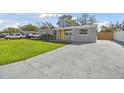 Well-maintained single-story home with a concrete driveway, vibrant lawn, and eye-catching yellow door at 8303 Croton Ave, Tampa, FL 33619