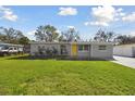 Inviting single-story home with lush green lawn, tidy landscaping, and a cheerful yellow door at 8303 Croton Ave, Tampa, FL 33619