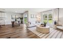 Open-concept living room featuring wood floors, a white sofa, a modern rug, and sliding glass doors to the backyard at 10861 Gentle Current Way, Parrish, FL 34219