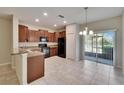 Modern kitchen with dark cabinetry, black appliances, granite counters, and an adjoining dining area at 12973 Dream Catcher Way, Riverview, FL 33579