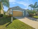 Lovely single-story home boasts lush green lawn, a beige garage door, and tropical landscaping for curb appeal at 13192 Royal Pines Ave, Riverview, FL 33579