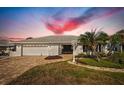 Charming single-story home with a brick driveway, two-car garage, and beautiful landscaping at dusk at 6322 Cottonwood Ln, Apollo Beach, FL 33572