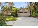 Charming home exterior with well-maintained landscaping, a large driveway and a two-car garage at 1235 Willowick Cir, Safety Harbor, FL 34695