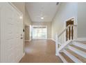 Bright, open entryway featuring tile flooring and a staircase with wood railings at 2105 Clover Hill Rd, Palm Harbor, FL 34683