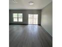 A spacious room with gray walls and flooring and a large window and glass sliding door at 2222 E Emma Street, Tampa, FL 33610