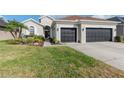 Charming home featuring a well-manicured lawn, a two-car garage and mature landscaping at 27045 Firebush Dr, Wesley Chapel, FL 33544