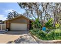 Inviting front yard with lush landscaping complementing this charming brick and siding home at 3089 Enisglen Dr, Palm Harbor, FL 34683