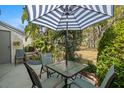 Cozy patio setting with a table, chairs, striped umbrella, and views of the manicured backyard at 3401 Killdeer Pl, Palm Harbor, FL 34685