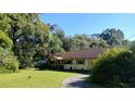 A well-maintained single-story home with mature trees and landscaping in a rural setting at 7608 Chenkin, Zephyrhills, FL 33540