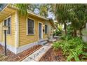 Exterior view of home showing charming yellow siding, landscaping and sidewalk to entry at 1045 6Th N St, St Petersburg, FL 33701