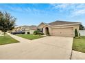 A tan single Gathering home is displayed with a manicured lawn and an attached two car garage at 12018 Gillingham Harbor Ln, Gibsonton, FL 33534