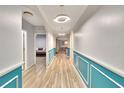 Bright hallway featuring wood-look floors, decorative wainscoting, and contemporary lighting fixtures at 12018 Gillingham Harbor Ln, Gibsonton, FL 33534