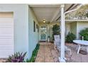 Inviting front porch with tiled flooring, outdoor seating, and manicured landscaping, creating a welcoming entrance at 1487 Dundee Dr, Palm Harbor, FL 34684