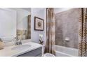 This well-lit bathroom features a shower with tiled walls, decorative shower curtain and a modern sink and vanity at 18005 Tavernside Trl, Lakewood Ranch, FL 34211