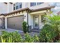 Inviting entrance showcasing a two-car garage, paver driveway, lush landscaping, and a stylish front door at 5095 San Martino Dr, Wesley Chapel, FL 33543