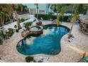 Aerial view of a private pool and spa, enhanced by decorative rock features and lush greenery at 614 Maryland Ave, Crystal Beach, FL 34681