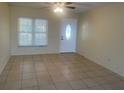 Bright living room featuring neutral paint, tile flooring, ceiling fan and a front door with decorative glass at 8969 109Th Ter, Seminole, FL 33777