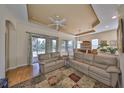 Bright living room features a ceiling fan, wood floors, large windows, and comfortable leather sofas at 918 Regal Manor Way, Sun City Center, FL 33573