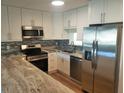 Modern kitchen boasts stainless steel appliances, sleek white cabinetry, and granite countertops, perfect for cooking at 9346 52Nd Way, Pinellas Park, FL 33782