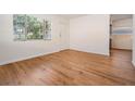 Inviting living room features hardwood floors, a window with blinds, and a white door at 3908 W Laurel St, Tampa, FL 33607