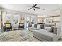 Spacious living room featuring neutral décor, large windows, grey sectional and blue accent chairs at 5134 Ballantrae Blvd, Land O Lakes, FL 34638