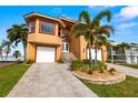 Charming two-story waterfront home with a well-manicured lawn, two-car garage, and a paver driveway at 854 Bay Point Dr, Madeira Beach, FL 33708