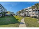 A serene lawn and walkway lead to a condo building with a manicured lawn and beautiful coastal views at 100 Bluff View Dr # 514A, Belleair Bluffs, FL 33770