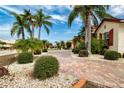 Beautiful brick driveway leads up to a home with lush landscaping featuring palm trees and manicured bushes at 1115 Signature Dr, Sun City Center, FL 33573
