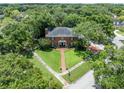 Aerial view of a brick home surrounded by lush greenery and a well-manicured lawn at 11806 Willow Point Way, Tampa, FL 33618