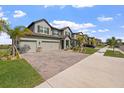 Beautiful two-story home with a three car garage, a brick paved driveway, and lovely landscaping at 3133 King Fern Dr, Wimauma, FL 33598