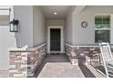 Front porch featuring a beautiful front door, stone accents, a 'Welcome' mat, and a rocking chair at 3133 King Fern Dr, Wimauma, FL 33598