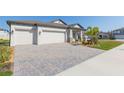 Paver driveway leads to the three-car garage, complemented by a well-maintained lawn and attractive landscaping at 33277 Rosewood Bark Way, Wesley Chapel, FL 33545