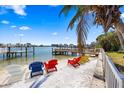 Waterfront backyard featuring beach, dock, and colorful adirondack chairs overlooking a picturesque view at 448 79Th S St, St Petersburg, FL 33707