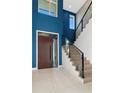 Elegant foyer featuring a modern wood door, staircase, and a vibrant blue accent wall at 4604 W Lowell Ave, Tampa, FL 33629