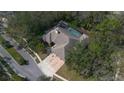 Aerial view of a large home with a screened pool area, lush trees, and a well manicured lawn at 70 Deerpath Dr, Oldsmar, FL 34677