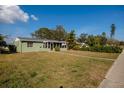 Traditional home with a green lawn, mature trees, and an enclosed porch at 775 40Th Ne Ave, St Petersburg, FL 33703