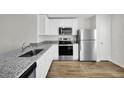 Modern kitchen featuring stainless steel appliances, granite countertops, and stylish wood flooring at 11073 Jackdaw Rd, Weeki Wachee, FL 34614