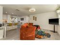 Modern living room with wood floors, a stylish orange couch, adjacent to a kitchen with bar stool seating at 2009 Douglas Ave, Dunedin, FL 34698