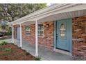 Inviting front porch featuring a brick facade, stylish light fixture, and a blue front door at 407 Cranberry Ln, Brandon, FL 33510