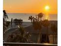 Balcony with a picturesque view of the ocean at sunset, featuring palm trees and nearby buildings at 7600 Bayshore Dr # 204, Treasure Island, FL 33706