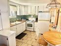 Cozy kitchen with white cabinetry, tile flooring, and dining table, perfect for casual meals at 9790 66Th N St # 206, Pinellas Park, FL 33782