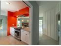 Bright kitchen featuring white cabinets, stainless appliances, and an orange accent wall at 10828 99Th Pl, Seminole, FL 33772