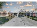 A single-story home featuring a carport, palm trees, and a concrete driveway at 13313 2Nd E St, Madeira Beach, FL 33708