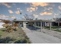 A single-story home featuring a carport, palm trees, and a concrete driveway at 13313 2Nd E St, Madeira Beach, FL 33708