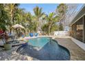 Beautiful backyard pool with sun loungers, umbrella, and lush landscaping for ultimate relaxation and privacy at 2460 Baywood E Dr, Dunedin, FL 34698