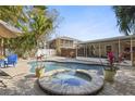 Inviting backyard featuring a pool and spa surrounded by lush greenery and comfortable seating at 2460 Baywood E Dr, Dunedin, FL 34698