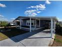 Inviting exterior view showcasing the home's covered parking, manicured lawn and front entry at 36830 Kimela Ave, Zephyrhills, FL 33542