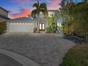 Beautiful home with a paver driveway, two-car garage, double door entry, and mature tropical landscaping at 1201 Bay Dr, Belleair Beach, FL 33786