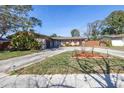 A well maintained single story home with rock facade and landscaped yard on a sunny day at 1816 Nursery Rd, Clearwater, FL 33764