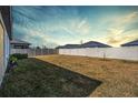 This spacious backyard features a modern white fence and fresh green sod with a view of the surrounding neighborhood at 31837 Cannon Rush Dr, San Antonio, FL 33576